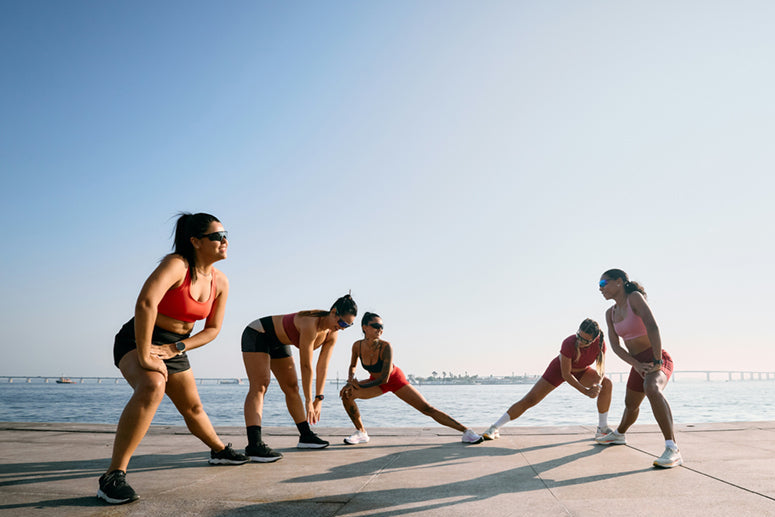 Group of people exercising on a concrete path by the beach.