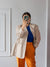Person wearing a beige blazer, blue top, and orange pants taking a mirror selfie.