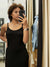 Woman taking a mirror selfie wearing a black dress in a store.